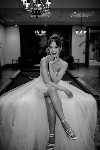 Bride at her wedding in Italy, sitting on a pool table and being photographer by a wedding photographer